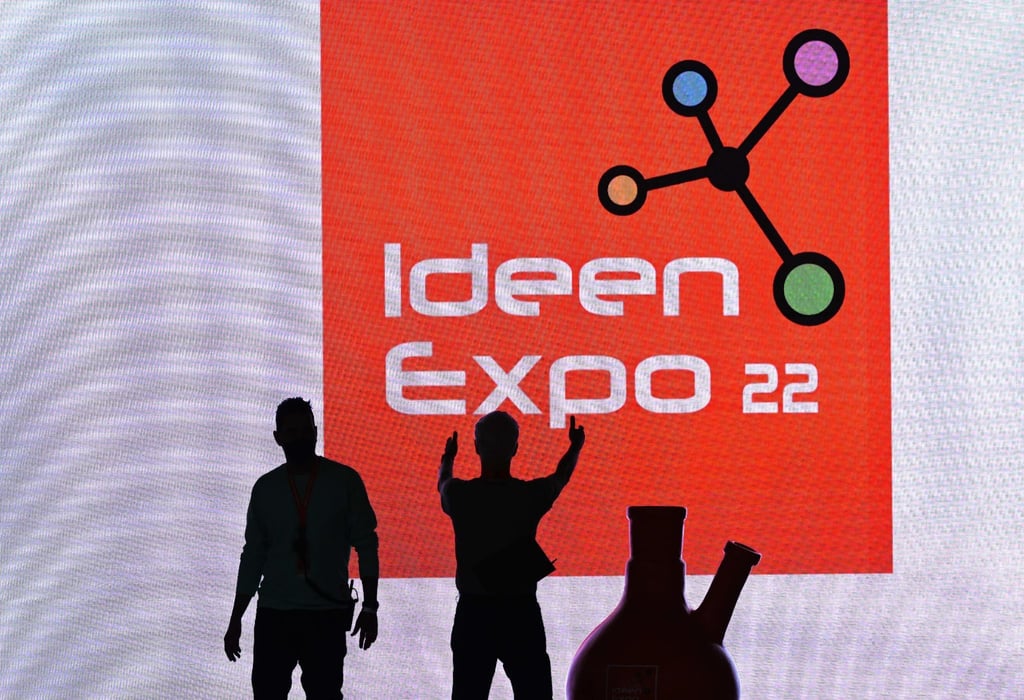Helfer stehen beim Aufbau für die IdeenExpo in der Messe Hannover vor einer Leinwand.