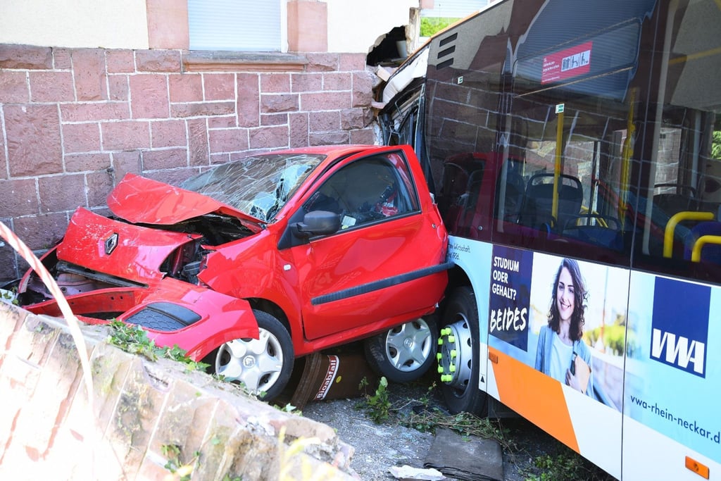 Ein zerstörtes Auto und der Linienbus, der in ein Haus gekracht ist.