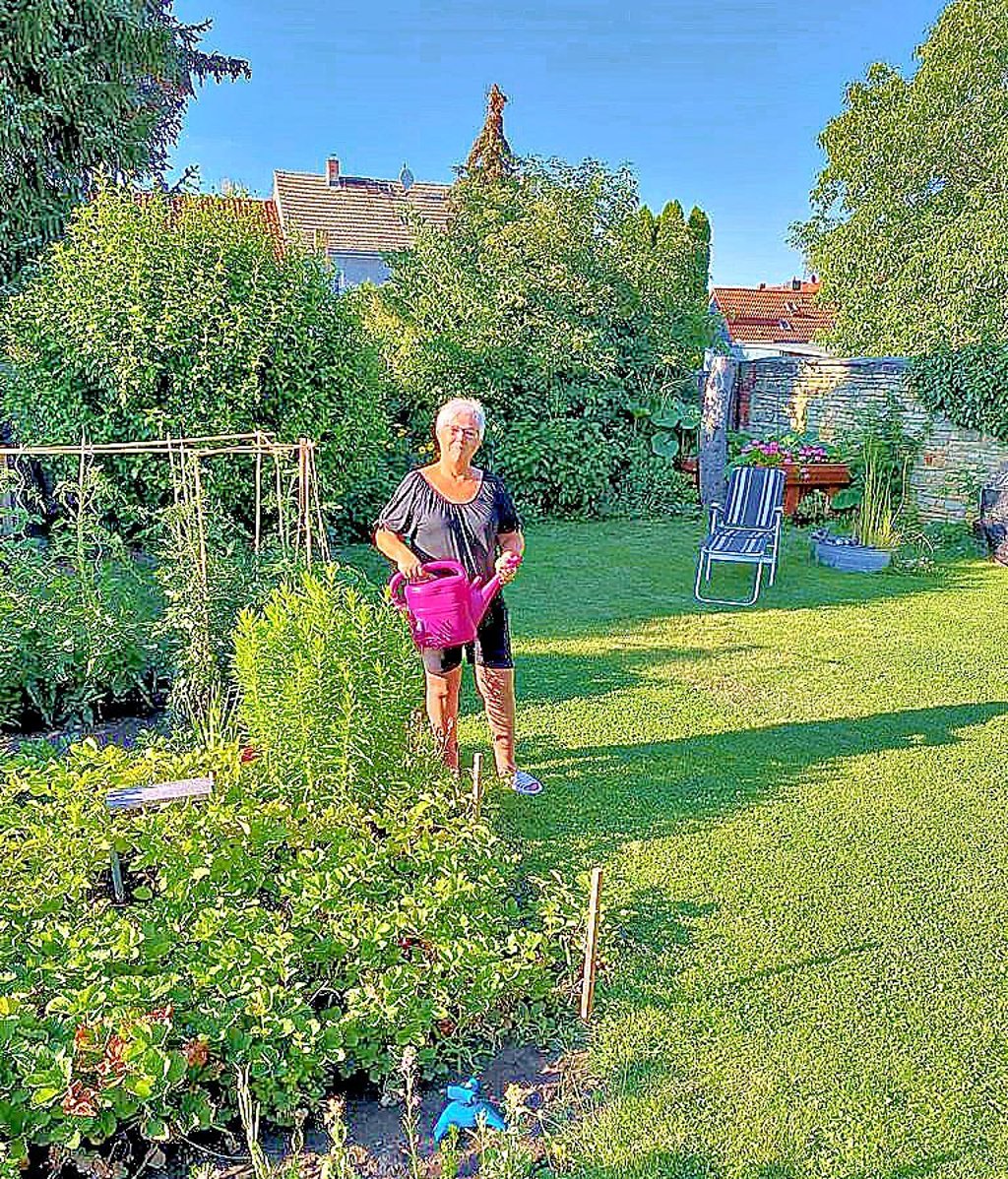 Heike Kaudelka aus Biere stellt die Szene nach. Als sie so gerade die Blumen goss, flog der rote Doppeldecker dicht über ihren Garten hinweg.
