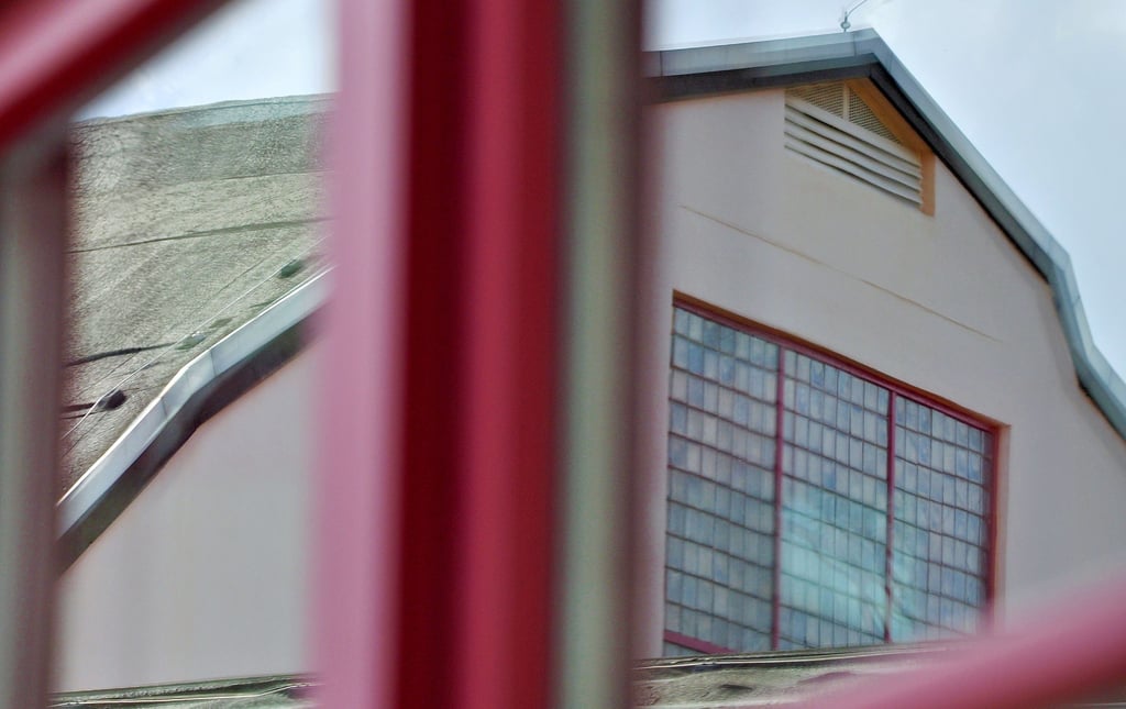 Die Fassade der Magdeburger Hermann-Gieseler-Halle spiegelt sich im Sprossenfenster eines Seitenflügels.