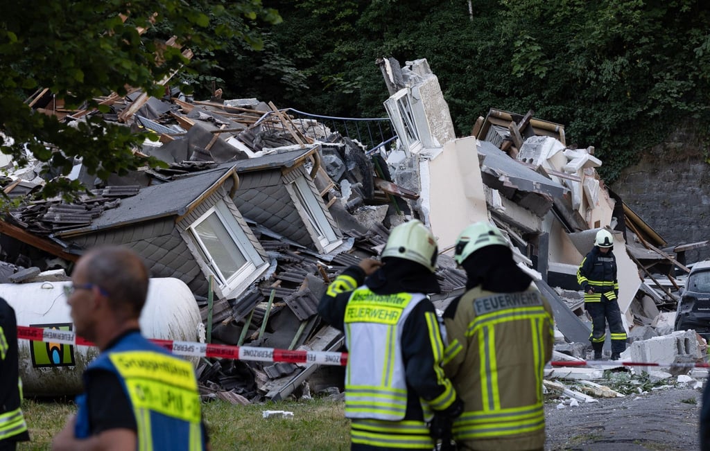 Feuerwehrleute stehen vor dem eingestürzten Haus in Hemer.