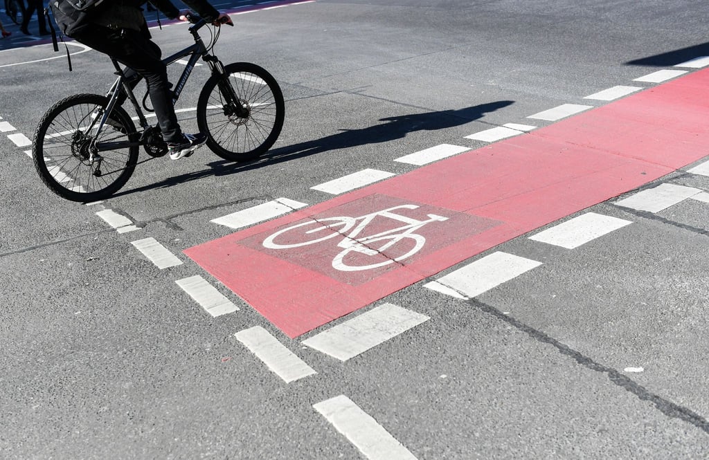 Ein Radfahrer fährt auf einer Straße neben einem rot markierten Radweg.