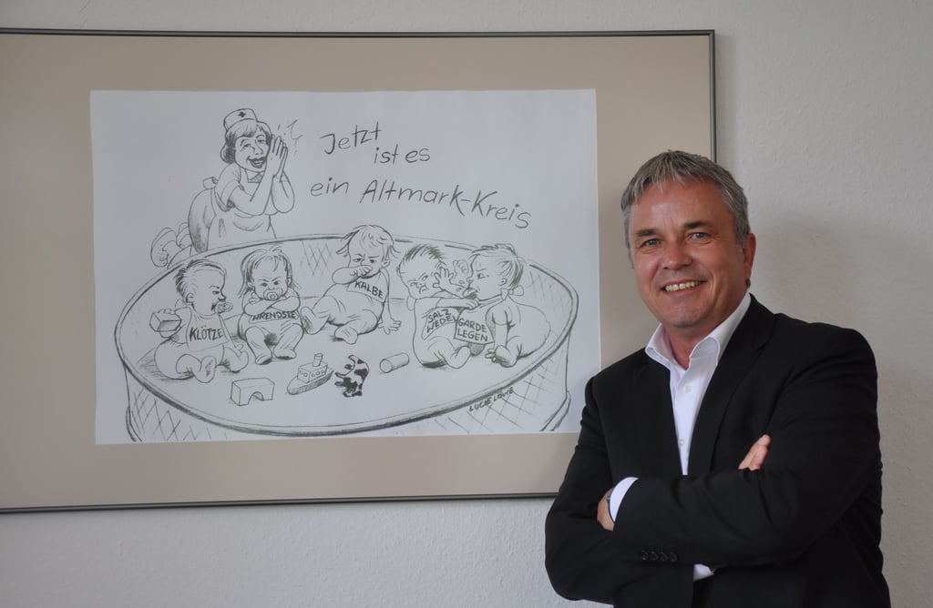 Landrat Michael Ziche vor der Karrikatur von Lucie Löwe in seinem Büro.