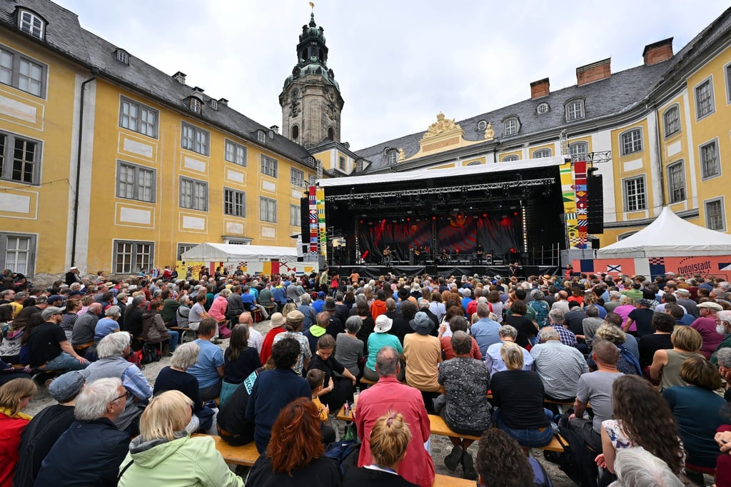 Besucher sitzen im Innenhof der Heidecksburg beim Konzert der Gruppe Light in Babylon aus Istanbul (Türkei) beim Rudolstadt Festival.