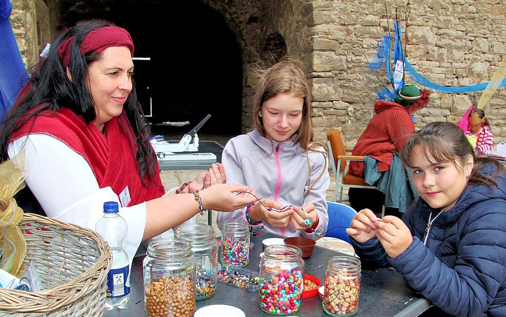 Daniela Rothmann (l.) lehrt Elena und Miriam, wie man ein Armband aus Glaskugeln herstellt.
