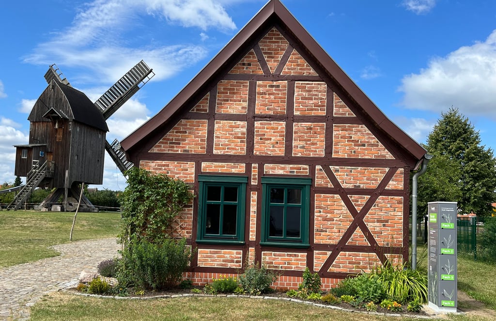 Die neue Ladesäule rechts am Backhaus in Grieben. Im Hintergrund die historische Bockwindmühle.