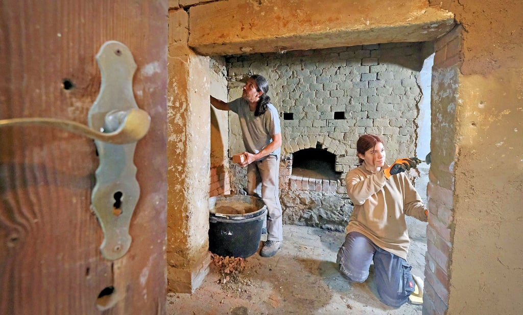 Paula Gödecke und Andreas Schael von der Jugendbauhütte helfen bei der Sanierung des Backhauses. Sie entfernen uralte Farbschichten.