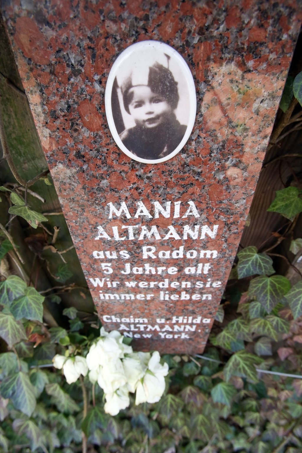 Ein Gedenkstein mit der Inschrift „Mania Altmann aus Radom, fünf Jahre alt, Wir werden sie immer lieben steht im Rosengarten der Hamburger Gedenkstätte Bullenhuser Damm.