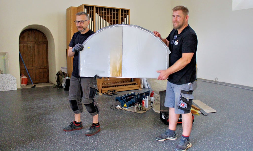 Joachim Fey und Philipp Schulz von den Derix Glasstudios Taunusstein setzen in der Eichholzer Kirche die neuen Glaskunstfenster ein.