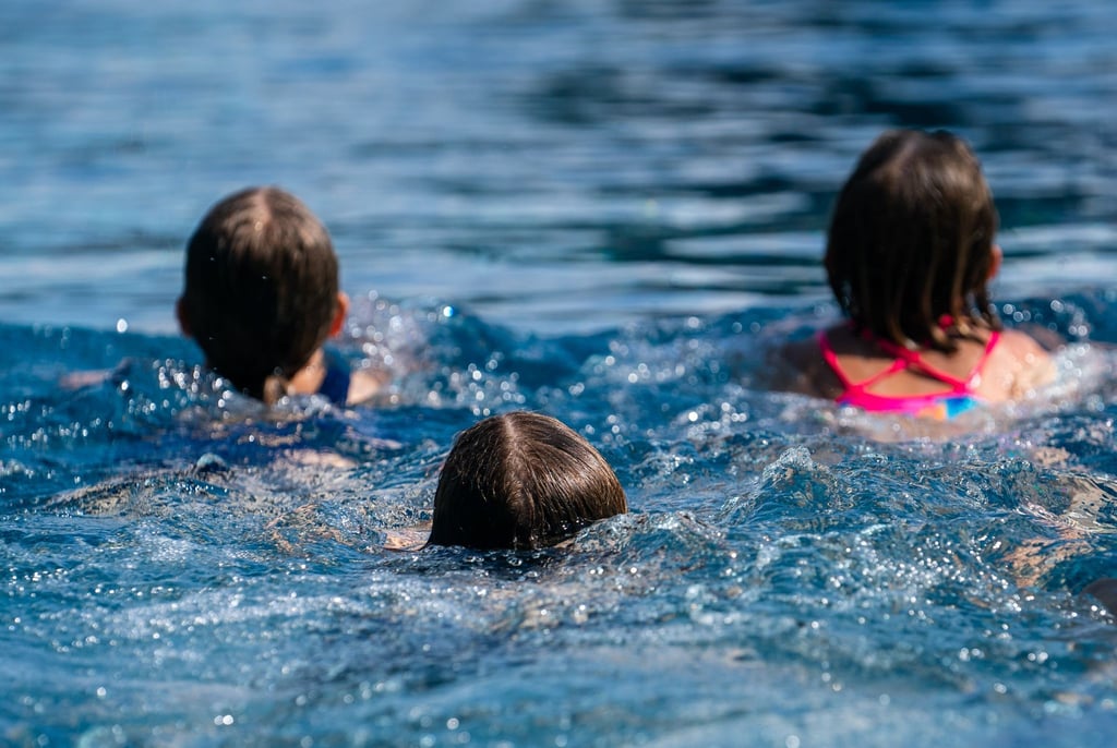 Kinder schwimmen in einem Schwimmbecken.