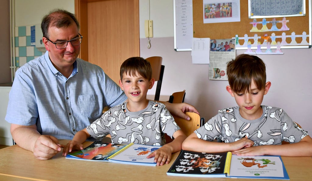 Der Schulleiter Frank Schiwek studiert mit Schülern ein Unterrichtsheft in ihrem Klassenraum.