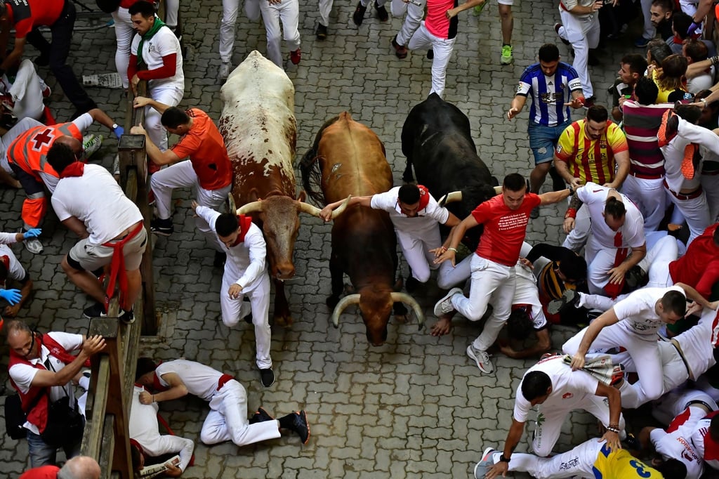 Läufer stürzen während des Stiertreibens beim San-Fermin-Festival.