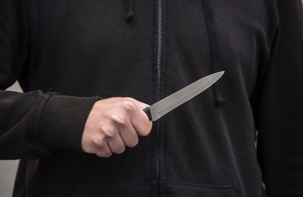 Ein Mann hält ein Messer vor dem Oberkörper (Symbolbild)
