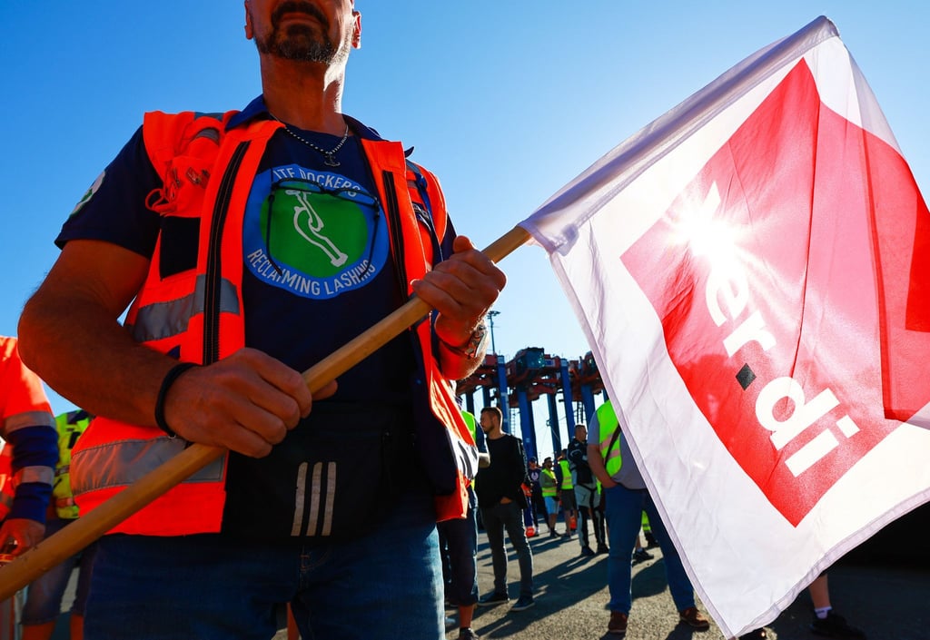Ein Hafenarbeiter hält eine Verdi-Fahne bei einem Warnstreik.