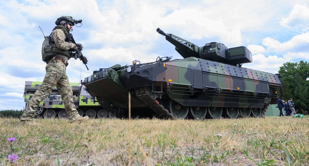 Ein "Infanterist der Zukunft" steht neben einem Schützenpanzer Puma des Rüstungskonzerns Rheinmetall.