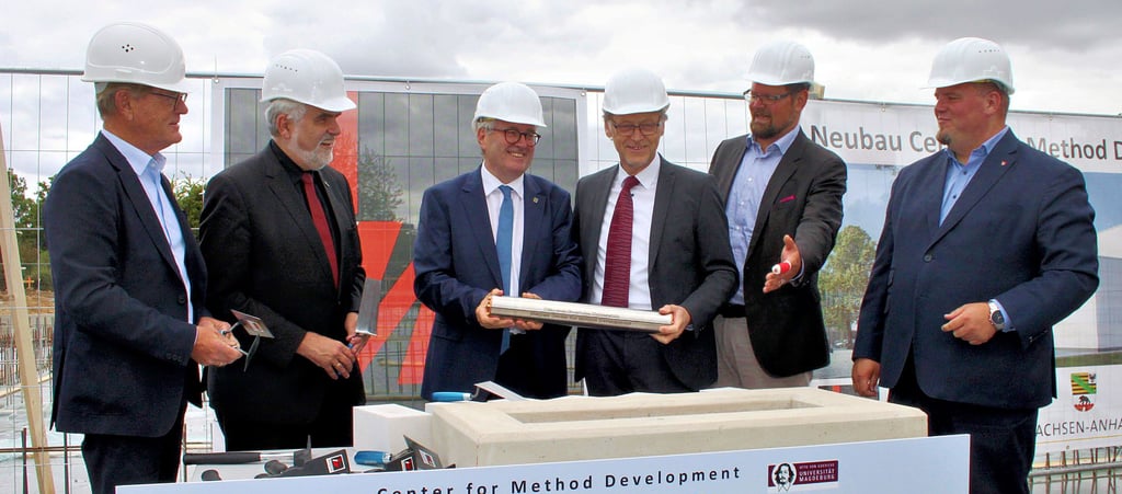 Bauprojektleiter Hans-Joachim Franzen, Minister Armin Willingmann, Staatssekretär Jürgen Ude, Uni-Rektor Jens Strackeljan, Landrat Martin Sticknoth und Bürgermeister Frank Nase (von links) versenken die Zeitkapsel in das Fundament des künftigen CMD-Gebäudes.