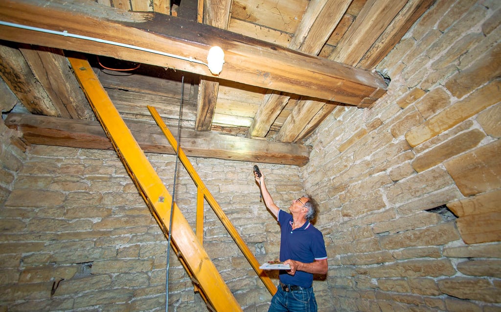 Ein Blick in das Innere des Kirchturmes in Predel. Holzschutzgutachter Joachim Malitte zeigt auf schadhafte Stellen im Bauwerk.