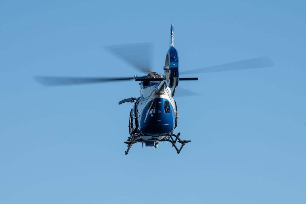Ein Polizeihubschrauber fliegt über ein Gewässer.