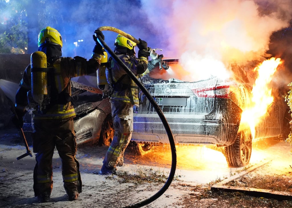 Feuerwehrleute löschen brennende Autos.