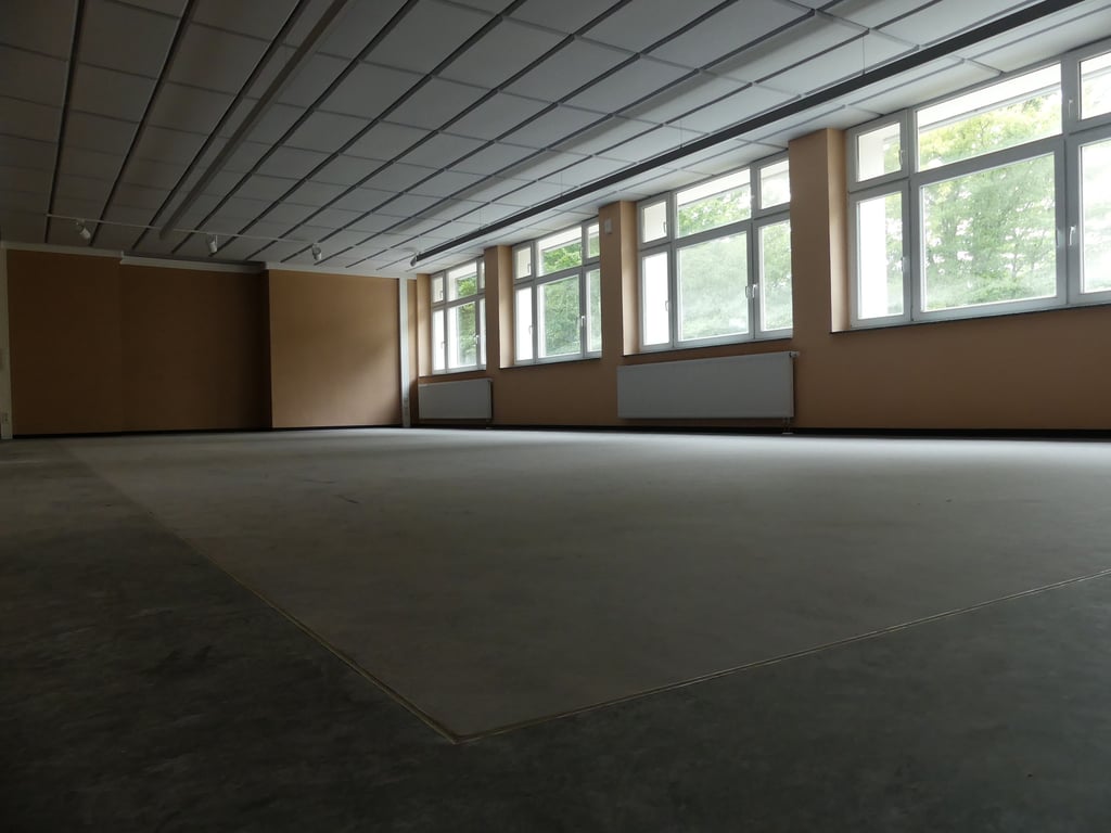 Das frühere Schwimmbad der Schule ist jetzt Aula. Im Boden lassen sich noch die alten Beckenumrisse erkennen.