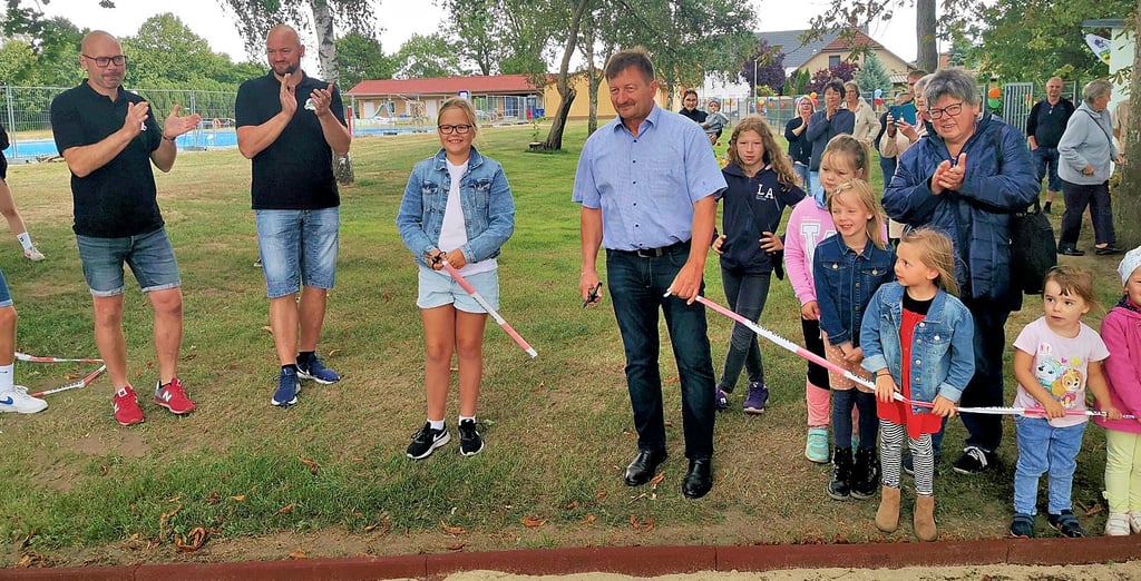 Hanna-Gerda Liebelt durfte mit Uwe Bartels das Band zum neuen Spielplatz durchschneiden. Frank Bartels und Robert Liebelt (links) applaudierten mit den Einwohnern.