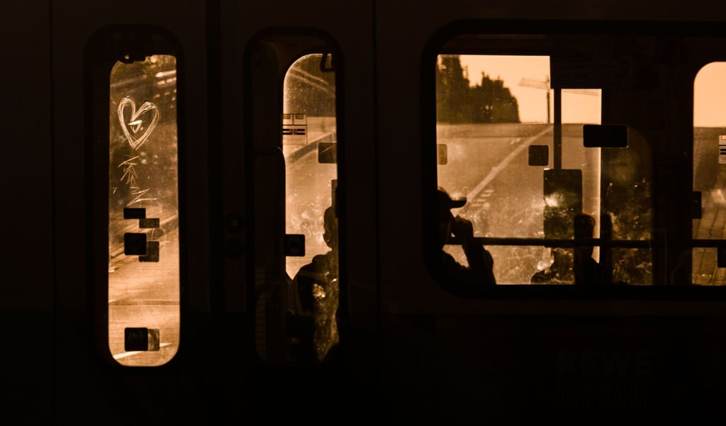 Fahrgäste sitzen am frühen Morgen bei Sonnenaufgang in einer Stadtbahn in der Region Hannover.