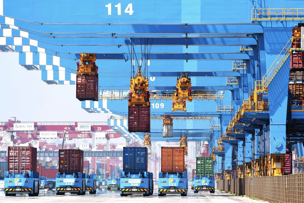 Portalkräne bewegen im Hafen von Qingdao im Osten Chinas Container auf Transporter.