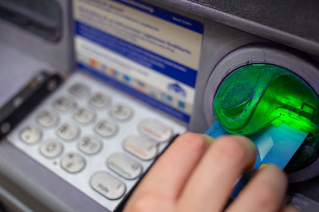 Eine Bankkundin steckt ihre Girokarte in einen Geldautomaten.