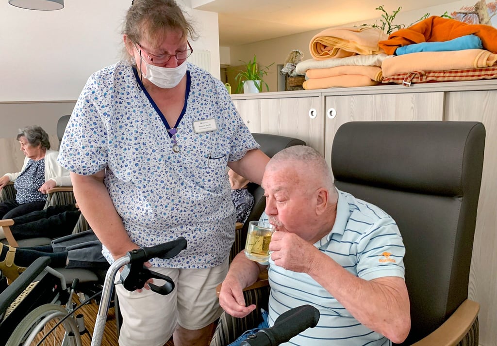 Simone Marth, Mitarbeiterin im Pflegezentrum Fuhneaue in Gröbzig, hat Willi Richter (83) ein Glas Apfelschorle serviert.