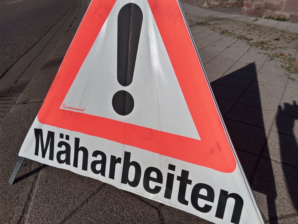 Ein Schild warnt vor Mäharbeiten.