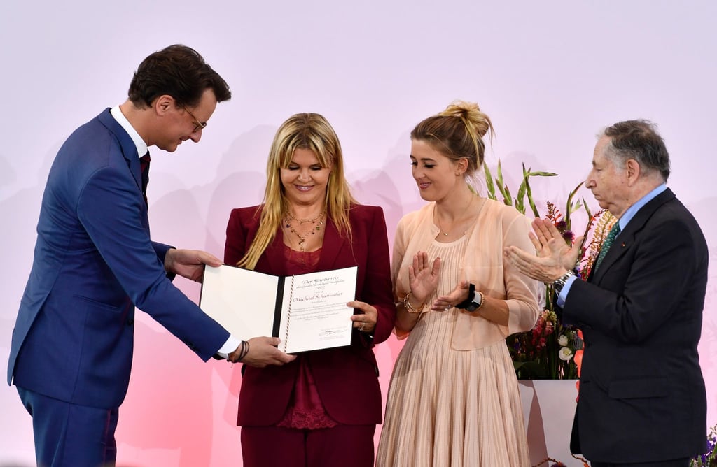 NRW-Ministerpräsident Hendrik Wüst (r) übergibt Corinna Schumacher und Tochter Gina die Auszeichnung - Ex-Ferrari-Teamchef Jean Todt (l) applaudiert.
