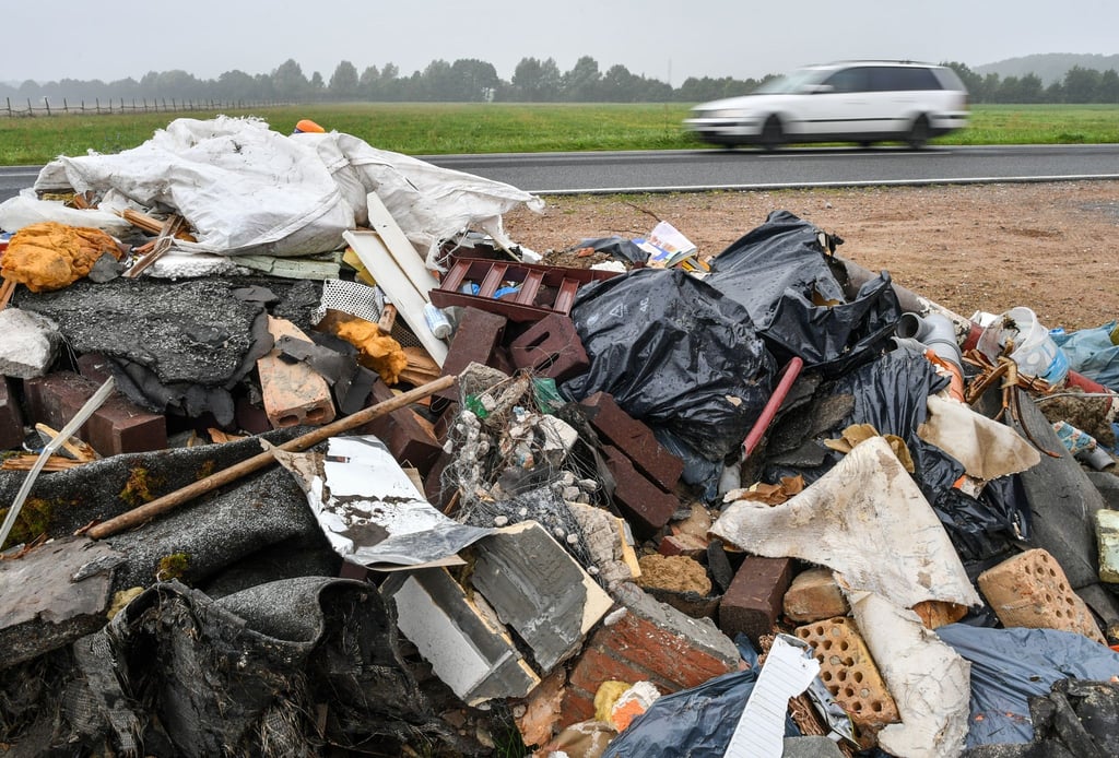 Ein großer Haufen Müll aus Bauschutt liegt neben einer Landstraße.