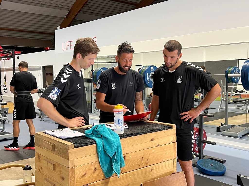 Cheftrainer Bennet Wiegert (Mitte) erklärt den beiden Neuzugängen Nikola Portner (l.) und Lucas Meister ihre Fitnessübungen.