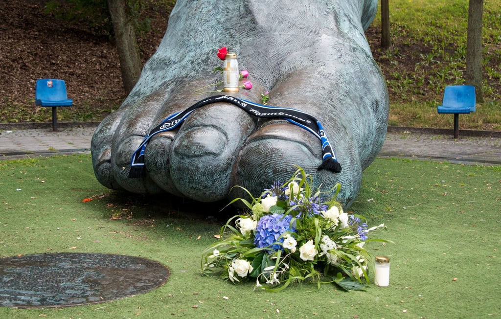 Blumen und Kerzen liegen an der überdimensionalen Bronzeskulptur vom rechten Fuß Seelers in Hamburg.