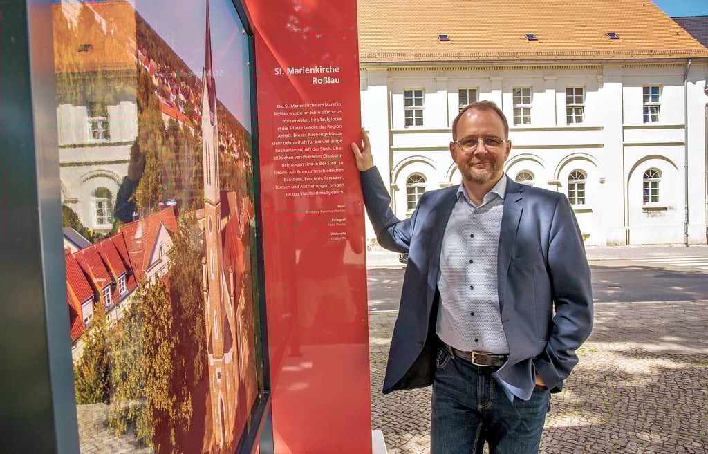Johannes Killyen, Pressesprecher der evangelischen Landeskirche Anhalt steht am Informationsschild über die St. Marienkirche in Roßlau.