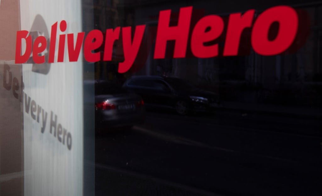 Das Logo des Essenslieferdienstes Delivery Hero spiegelt sich in einer Fensterscheibe.