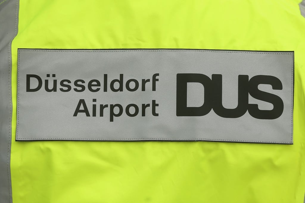 Ein Flughafen-Schriftzug mit dem Aufschrift „Düsseldorf Airport DUS“ auf eine Warnweste.