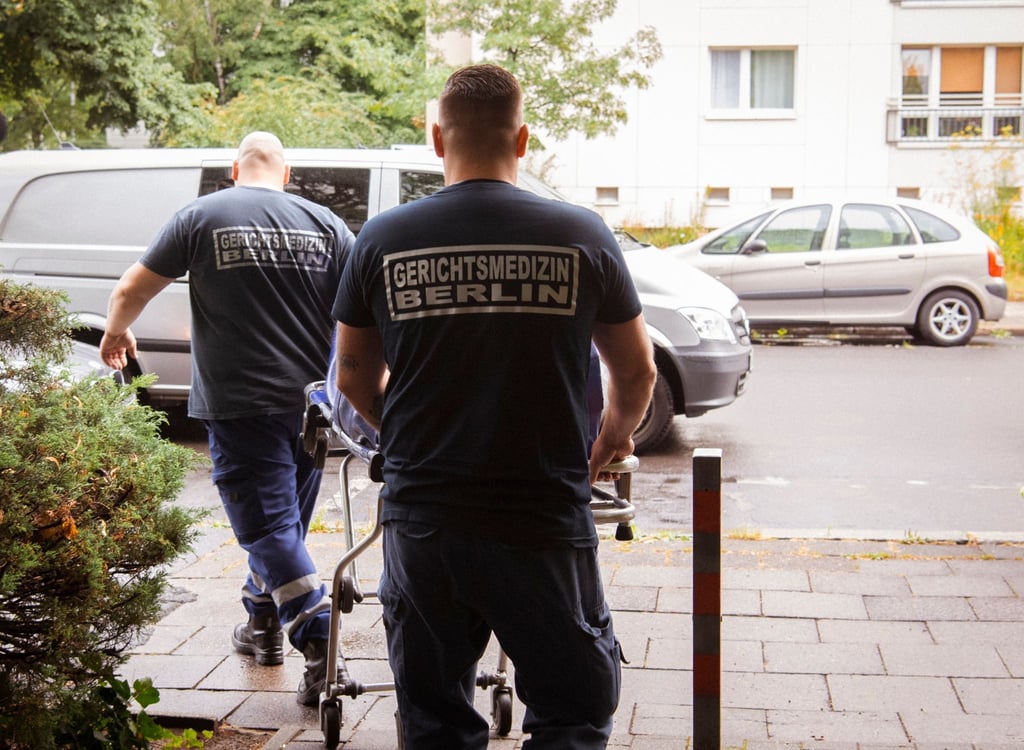 Mitarbeiter der Gerichtsmedizin transportieren eine Leiche aus einer Wohnung in einem Mehrfamilienhaus in der Singerstraße zu ihrem Fahrzeug.
