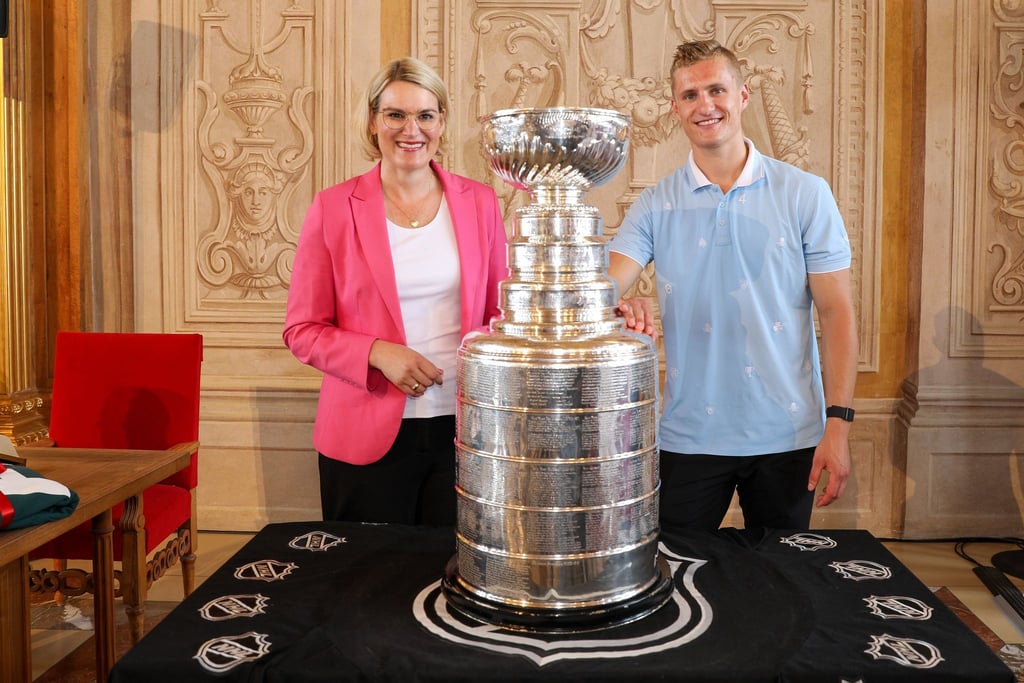 Eva Weber, Oberbürgermeisterin von Augsburg, und Nico Sturm posieren mit dem Stanley Cup.