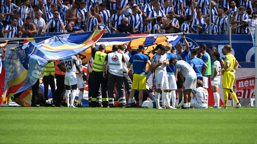 Spieler und Ordner schirmten Jamie Lawrence nach seinem Zusammenbruch nach dem Spiel des FCM in Karlsruhe ab.&nbsp;