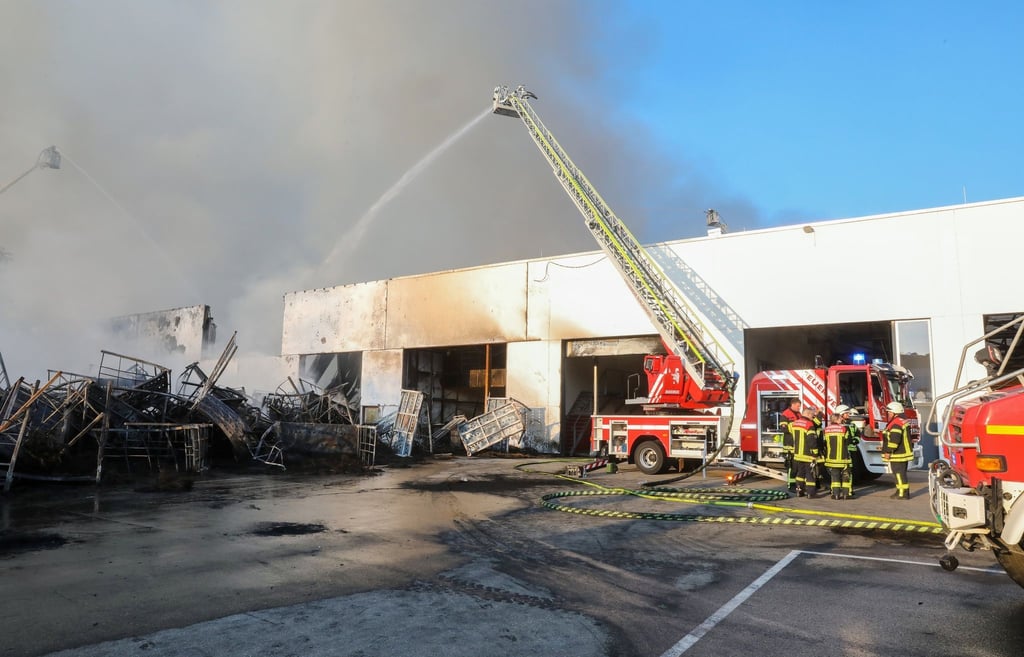 Einsatzkräfte der Feuerwehr stehen während eines Großbrandes auf dem Gelände des Reifengroßhändlers in Gammertingen in Baden-Württemberg und löschen das Feuer.