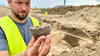 Grabungsleiter Christian Feddern zeigt eine Tasse aus der Jungsteinzeit, die auf dem künftigen Avnet-Gelände gefunden wurde.  