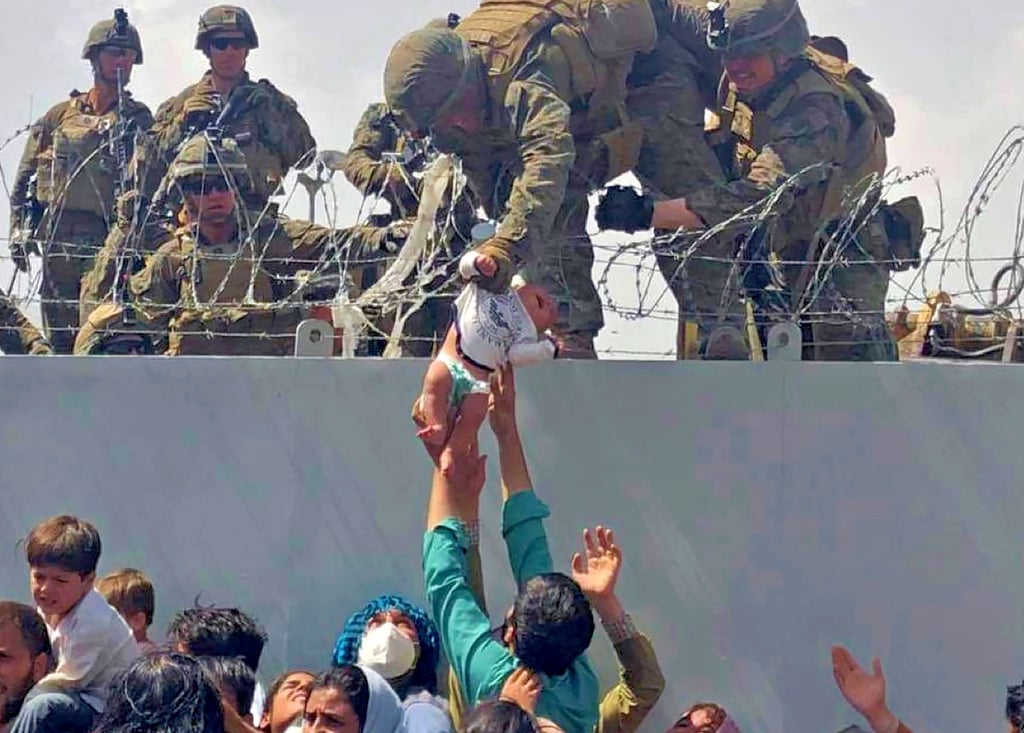 Dieses Bild zeigt ein Baby, das im August 2021 in all dem Chaos von US-Soldaten über eine Mauer am Flughafen von Kabul gehoben wird. Irgendwo in dieser Menschenmenge warteten auch Jawid und seine Frau auf ihre Ausreise.