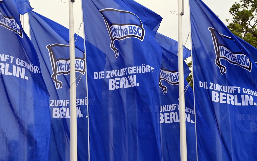 Blaue Flaggen mit dem Hertha-Logo und der Aufschrift „Die Zukunft gehört Berlin“ sind vor dem Eingang zu den Messehallen aufgebaut.