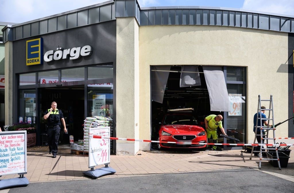 Ein Kleinwagen steht nach einem Unfall im Fenster eines Edeka-Supermarktes.