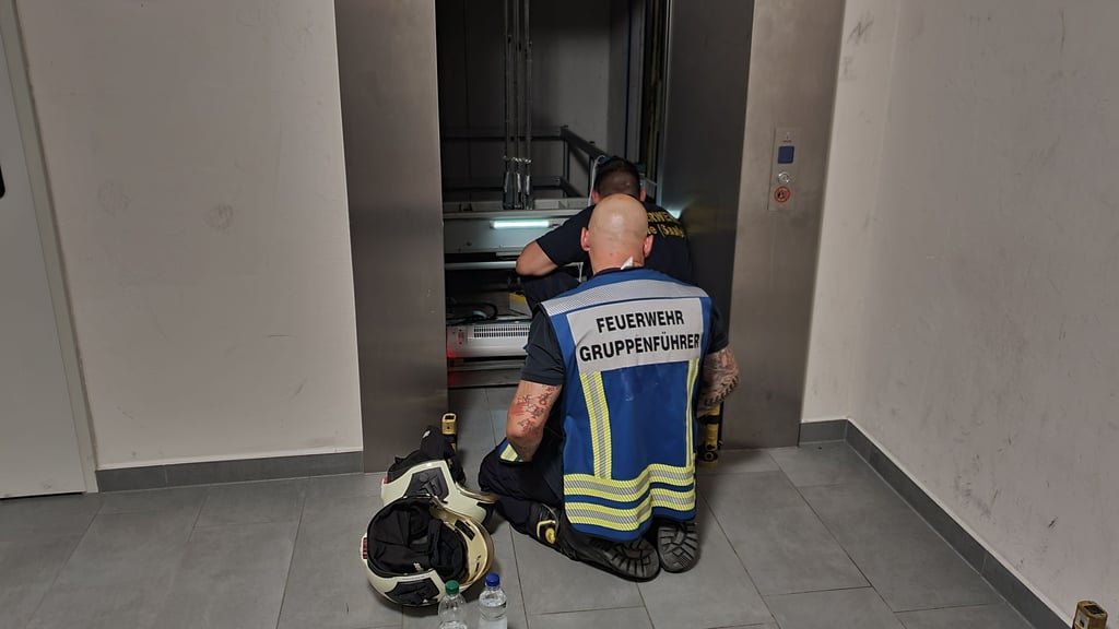 In Halle-Neustadt steckten am Donnerstagabend mehrere Kinder stundenlang in einem Aufzug fest. Feuerwehrleute versorgen die Kinder im Fahrstuhl.