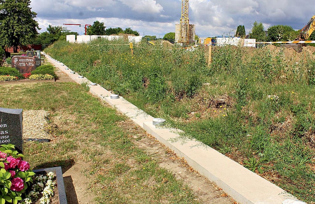 Das Fundament ist gesetzt, doch die Neuerrichtung der Mauer lässt auf sich warten. Trotz des Erdwalls sind die Bauarbeiten im neuen Wohngebeit gleich neben dem Friedhof allgegenwärtig.