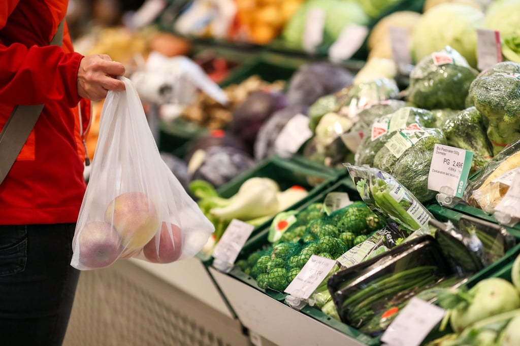 Eine Kundin steht in der Obst- und Gemüseabteilung eines Supermarkts.