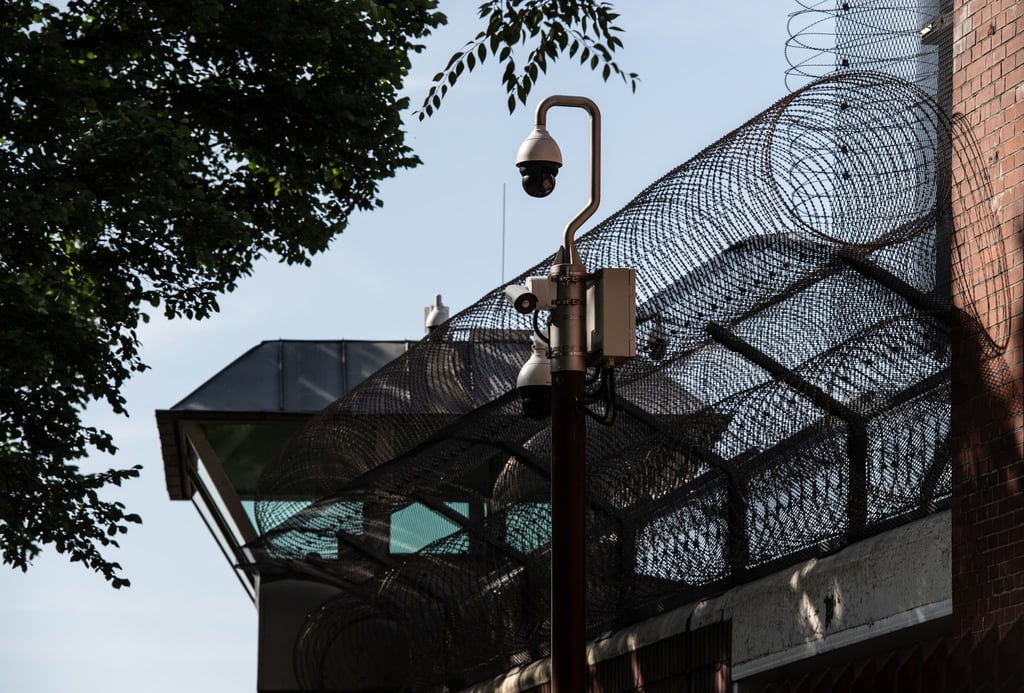 Ein Wachturm der Justizvollzugsanstalt (JVA) Moabit wird von einem Sicherheitszaun eingerahmt.