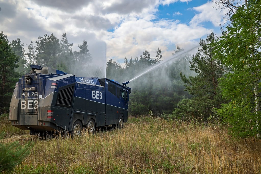 Ein Wasserwerfer der Brandenburger Polizei löscht einen Waldbrand.